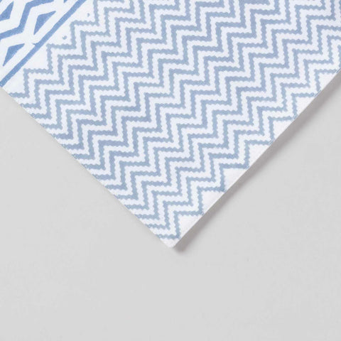 Close-up corner view of a blue lily hand block printed table runner highlighting floral vine motifs and  zig-zag pattern on cotton texture