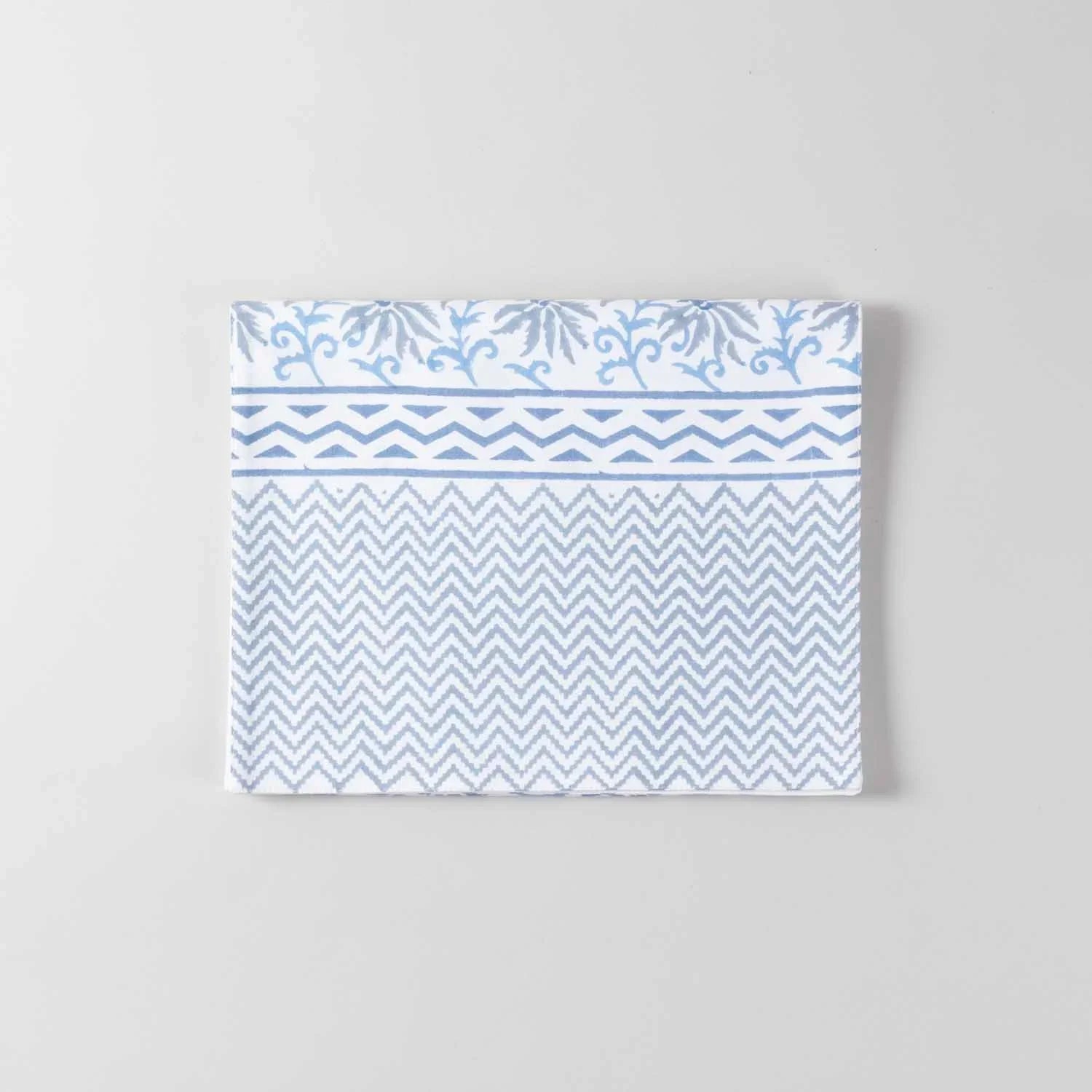 Folded blue lily floral block printed cotton table runner with zigzag patterned border showcasing handcrafted detailing on a white base