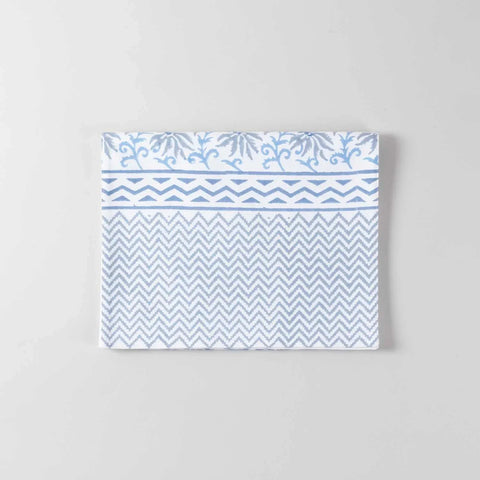 Folded blue lily floral block printed cotton table runner with zigzag patterned border showcasing handcrafted detailing on a white base