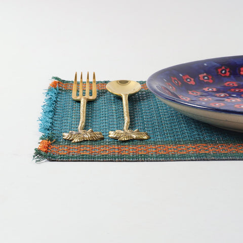 Handmade blue Madhurkathi table mats styled on a dining table with cutlery and ceramic plates, creating an elegant table setting