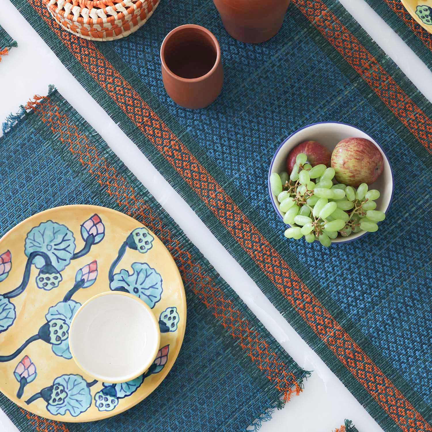 Dining table setting with a blue Madurkathi table runner and placemats set featuring natural river grass weave and handcrafted table decor