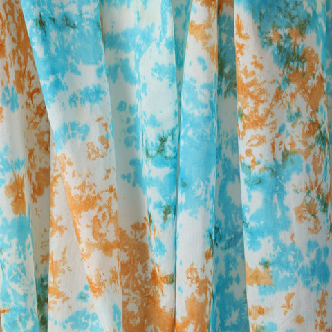 Close-up of the handcrafted blue and orange tie-dye pattern on soft mulmul cotton curtain fabric.