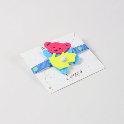 Angled view of the handmade blue and yellow Teddy Bear Felt Kids Rakhi attached to a festive Best Wishes card for Raksha Bandhan gifting