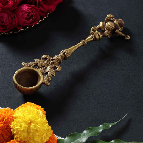 Brass hawan spoon with  Dancing Ganesha  motif handle styled in a traditional puja setup, showcasing spiritual and festive use