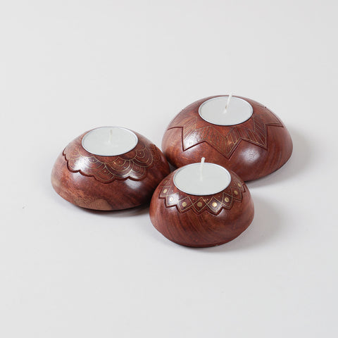 Angled view of a brass inlay wooden T-light holder set showcasing handcrafted star, lotus, and scalloped designs in varying sizes