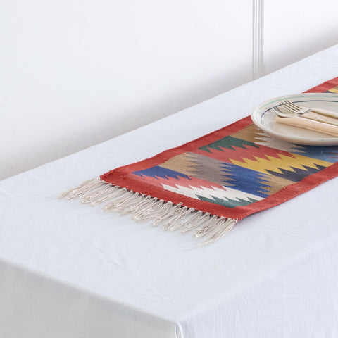 Detailed fringe tassels view of a styled cotton floor or table runner featuring multicoloured geometric motifs and red border detailing