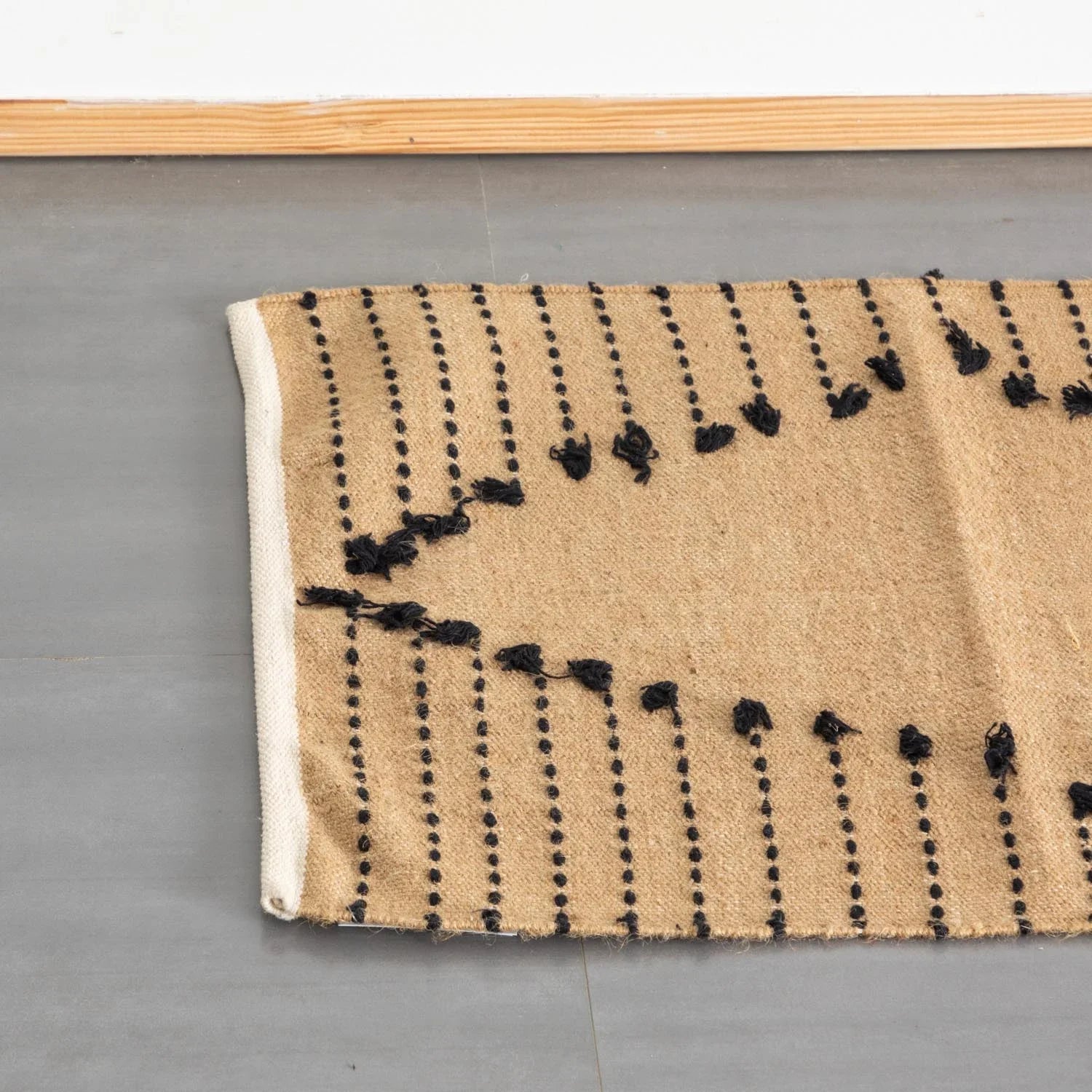 Top view of a brown cotton dhurrie rug highlighting black dotted stripe patterns and woven detailing