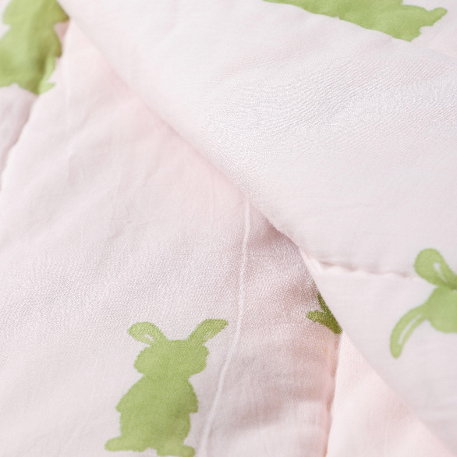 Detailed close-up of bunny and carrot block printed cotton quilt fabric showing stitching, handcrafted motifs, and breathable cotton texture