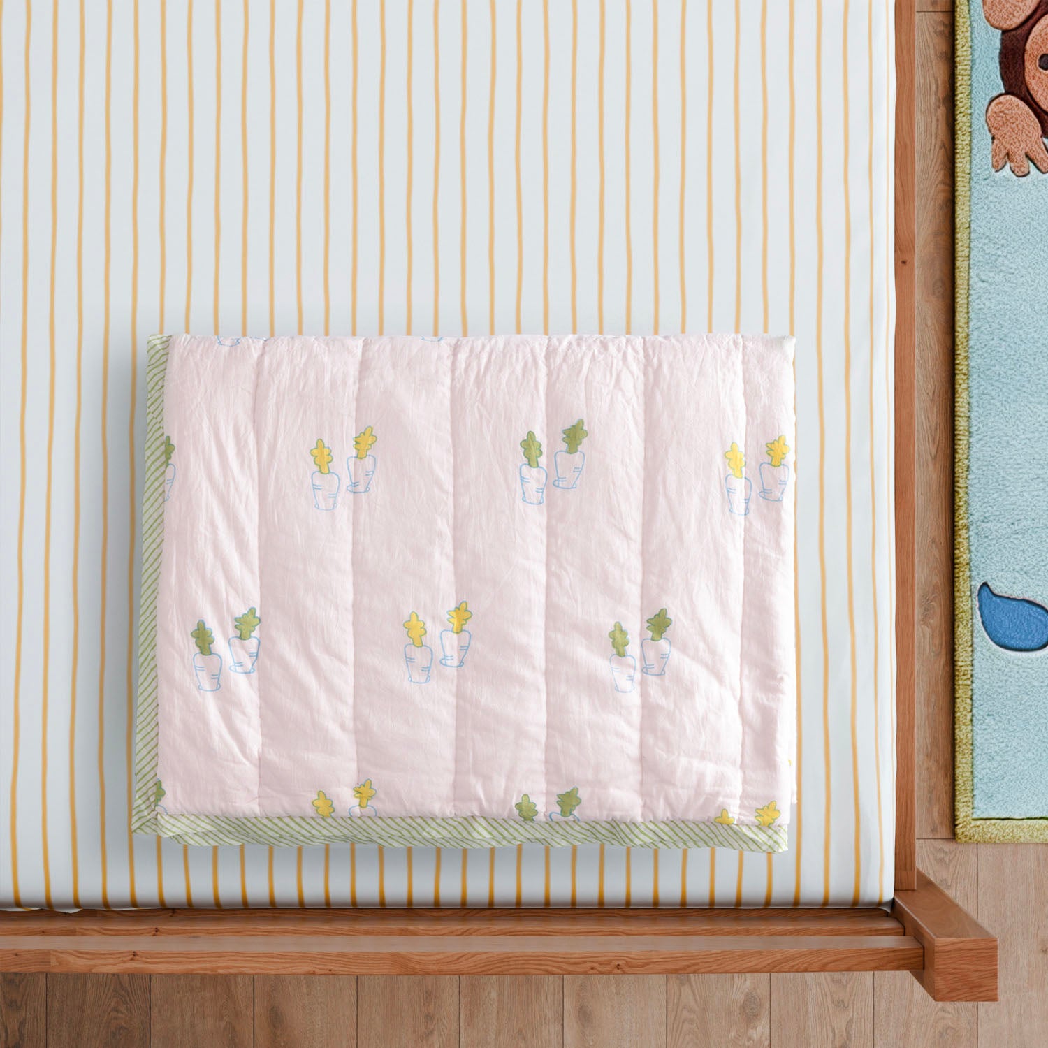 Styled close-up of a hand block printed cotton quilt featuring bunny and carrot motifs, showcasing detailed artisan printing and soft cotton fabric