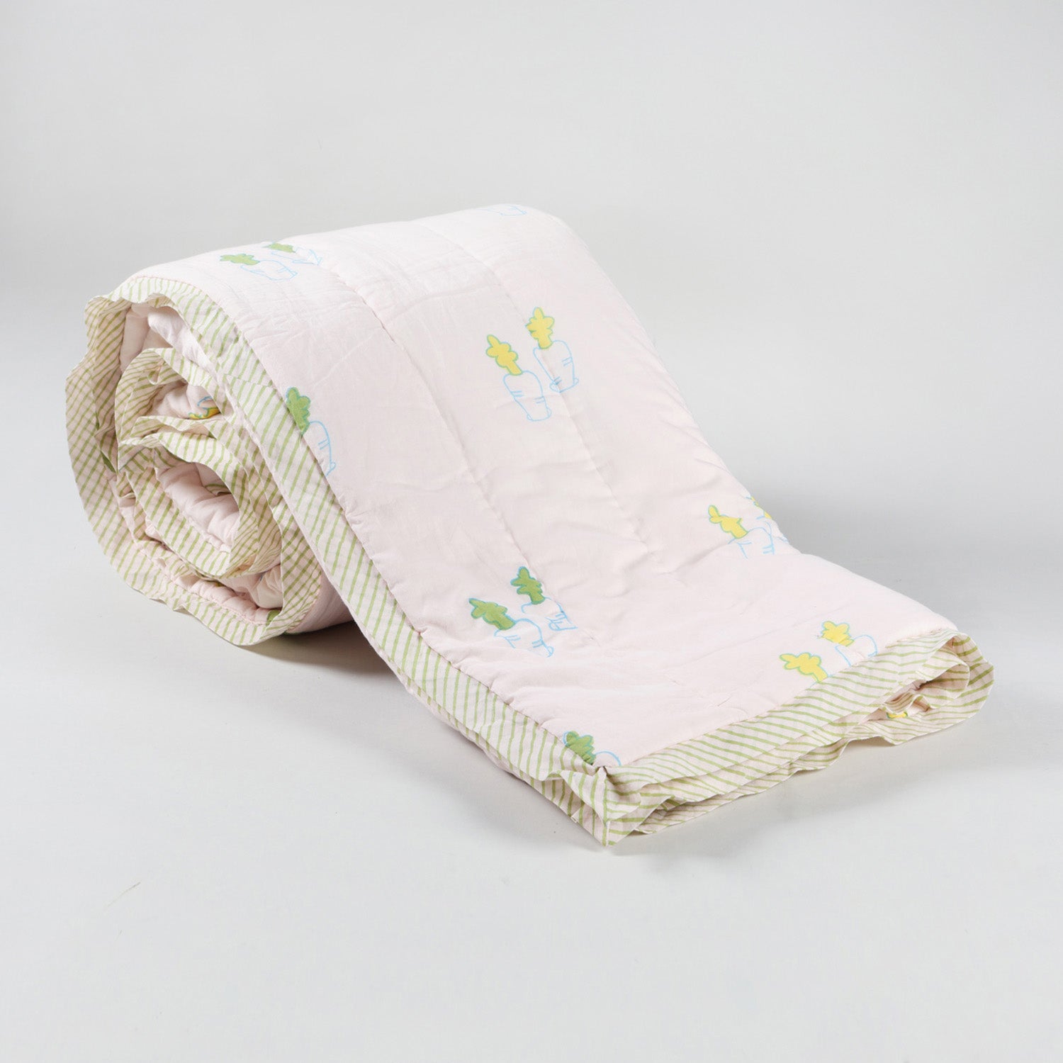 Rolled cotton quilt with bunny and carrot block prints, highlighting the layered quilting and breathable cotton fabric