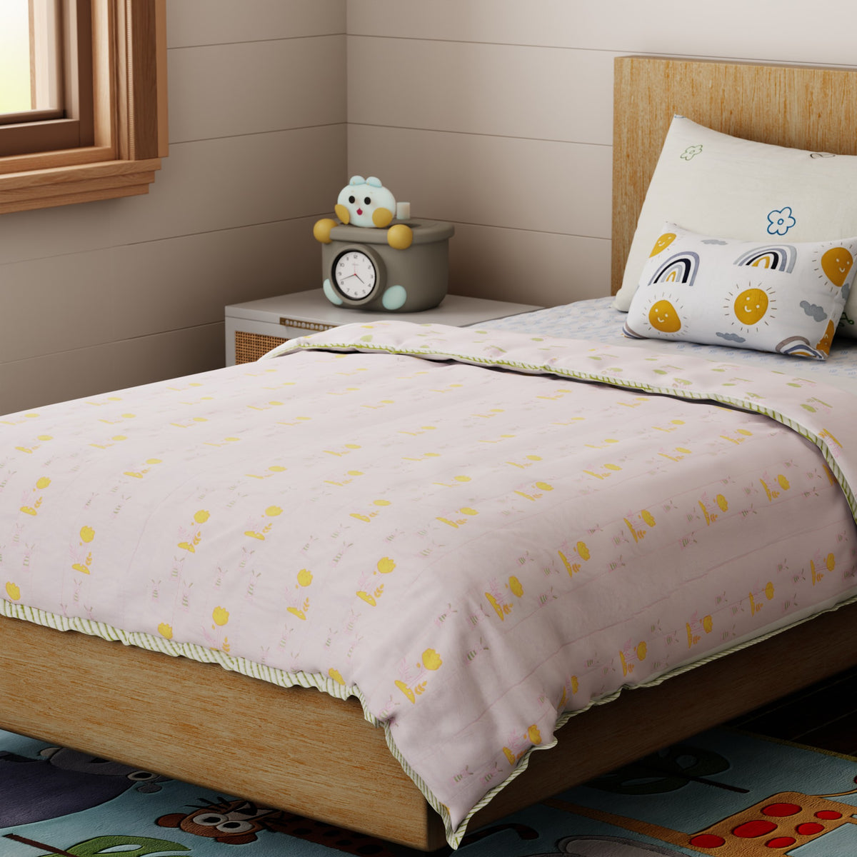 Hand block printed cotton quilt featuring bunny and tree motifs in soft pink, green, and yellow tones, styled on a single bed for a cozy kids room