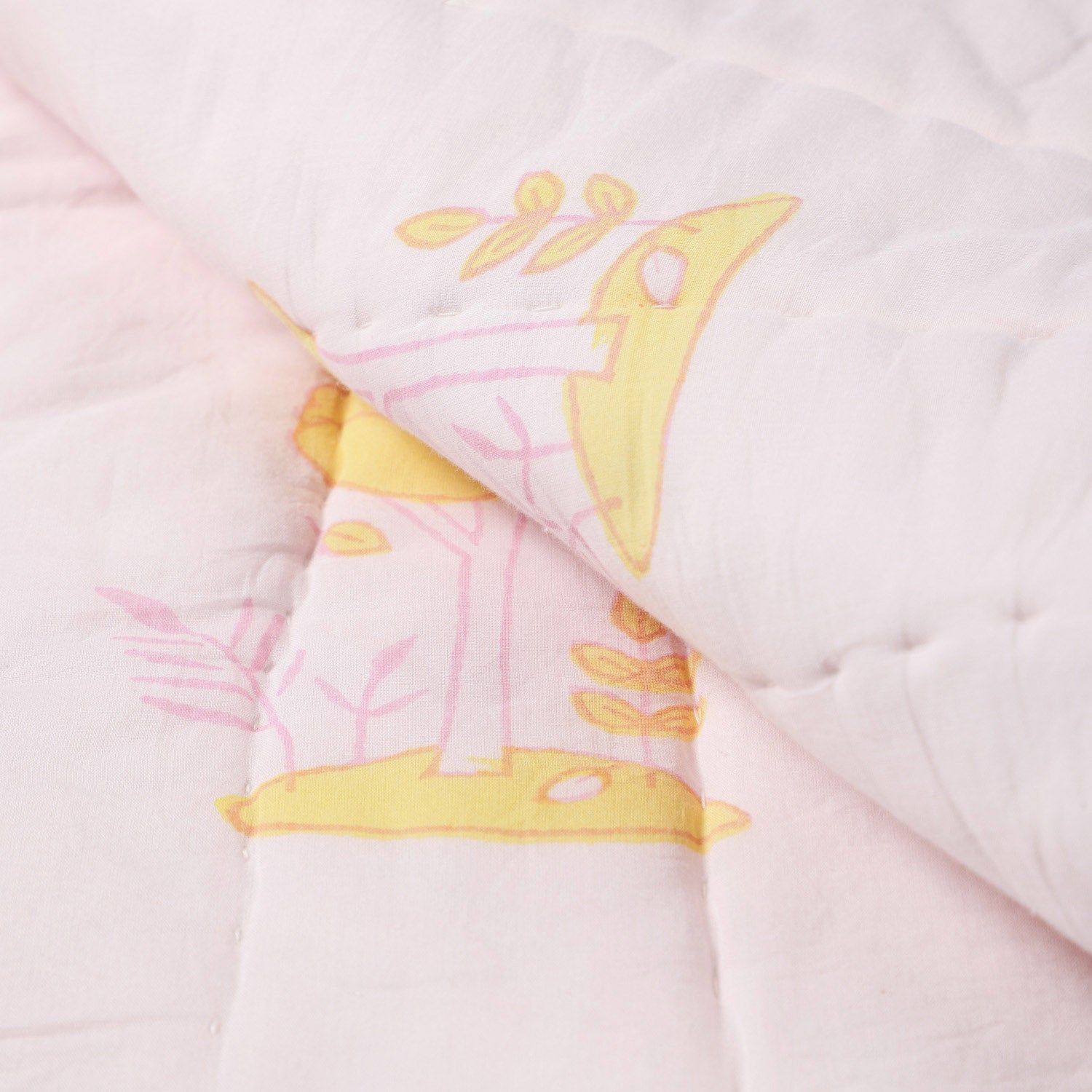 Detailed close-up of hand block printed bunny and tree motifs on a cotton quilt, showcasing artisan craftsmanship and stitching
