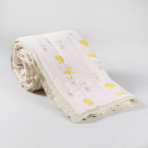 Rolled 60x90 reversible cotton quilt featuring playful bunny and tree motifs in pastel colours on a light pink background