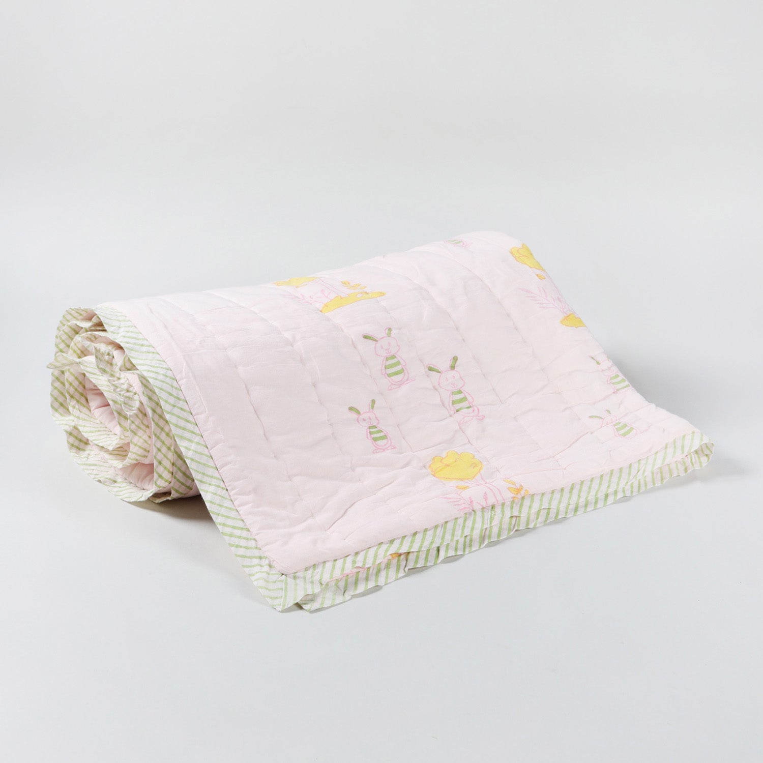 Cotton quilt with repeating bunny and tree block print motifs on a light pink base, handcrafted for kids and everyday use
