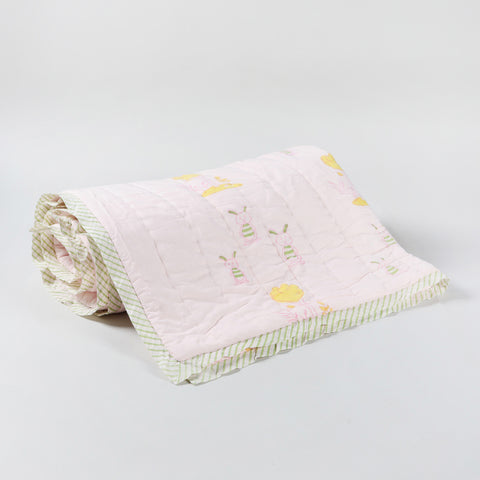 Cotton quilt with repeating bunny and tree block print motifs on a light pink base, handcrafted for kids and everyday use