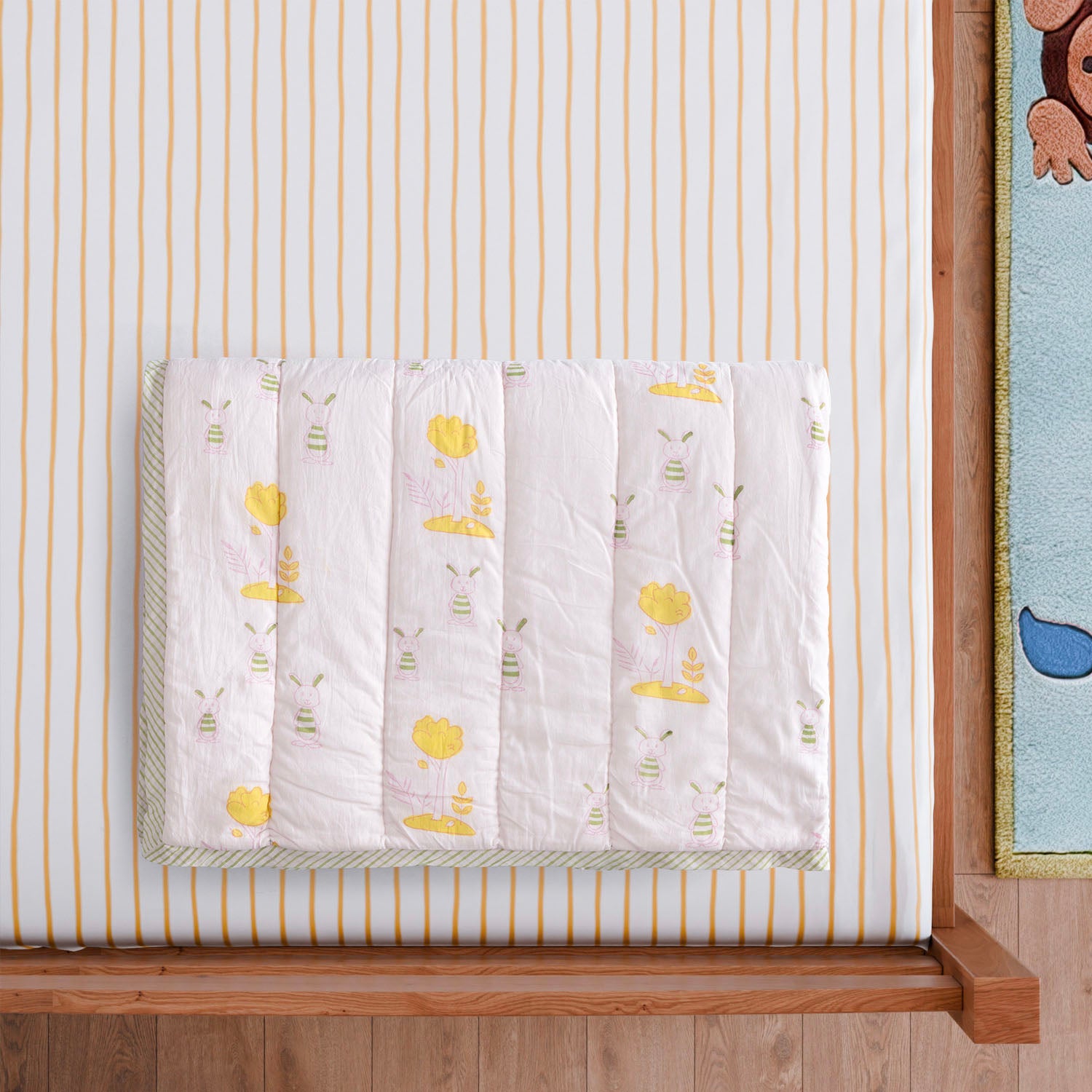  Styled close-up of a folded hand block printed cotton quilt featuring bunny and tree motifs, showcasing breathable cotton fabric and detailed artisan printing