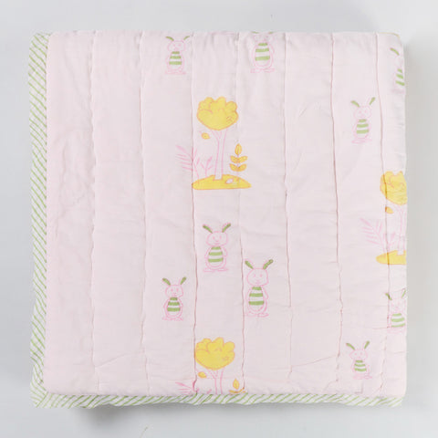 Folded hand block printed cotton quilt showcasing bunny and tree motifs, soft cotton fabric, and reversible construction