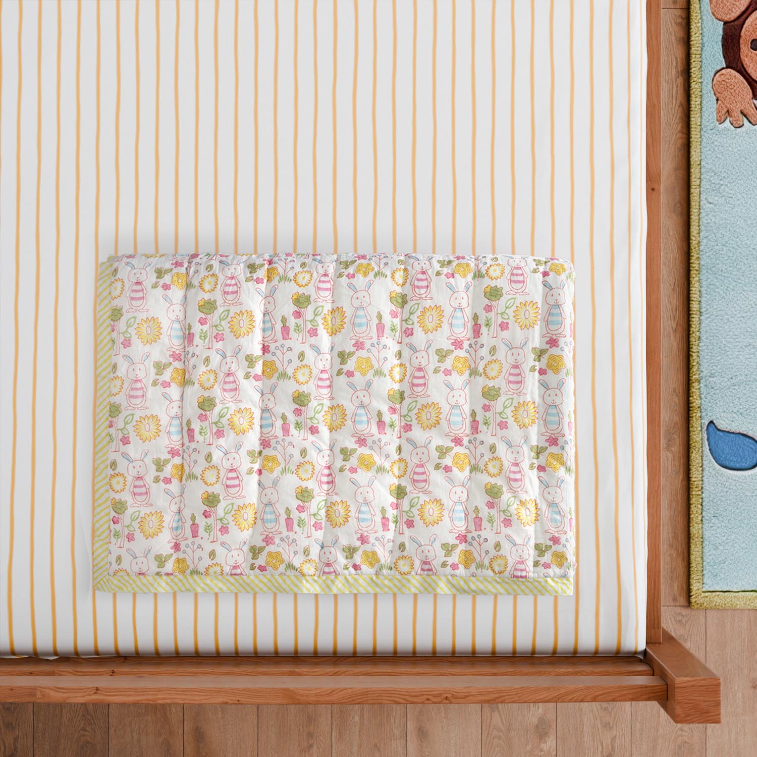 Styled close-up of a hand block printed cotton quilt with bunny garden motifs, showcasing soft cotton texture and detailed printing
