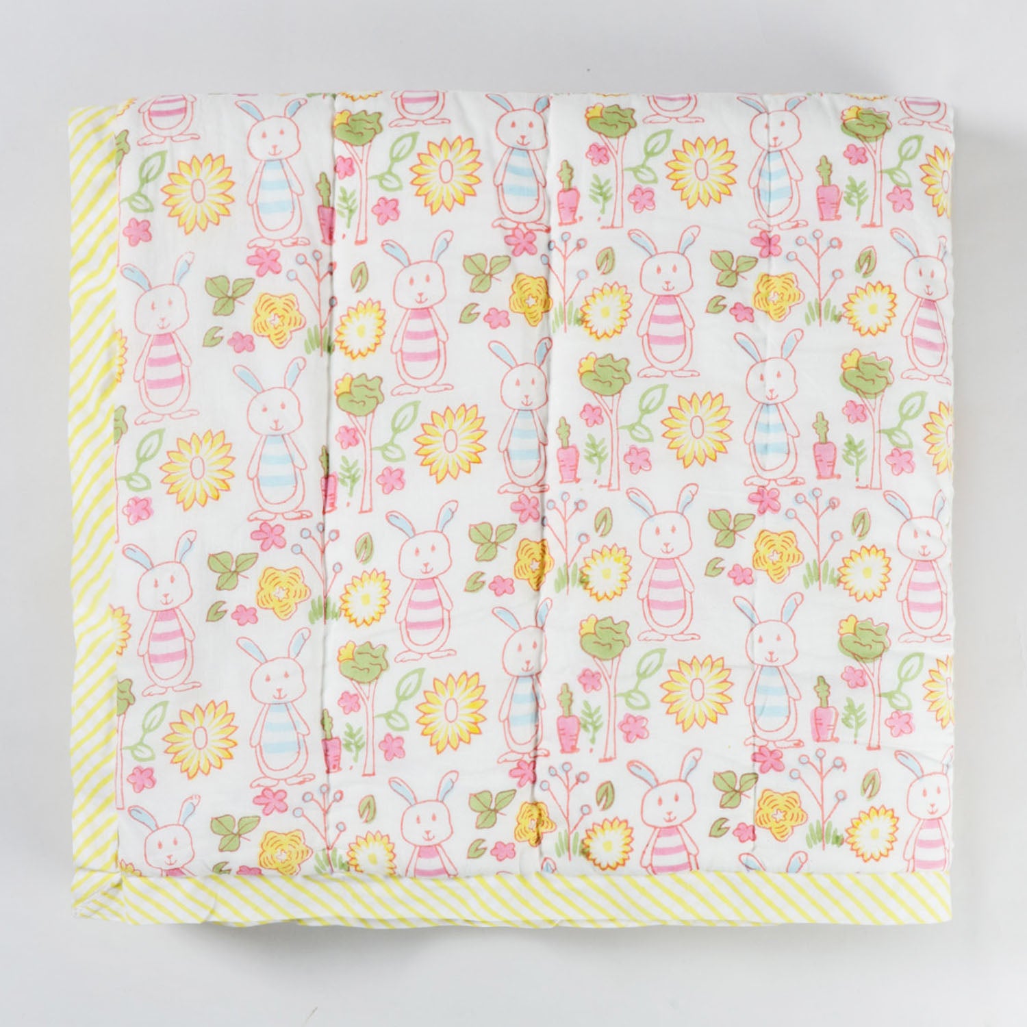 Folded hand block printed cotton quilt featuring bunny and garden motifs, highlighting soft breathable cotton fabric and lightweight texture