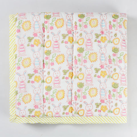 Folded hand block printed cotton quilt featuring bunny and garden motifs, highlighting soft breathable cotton fabric and lightweight texture