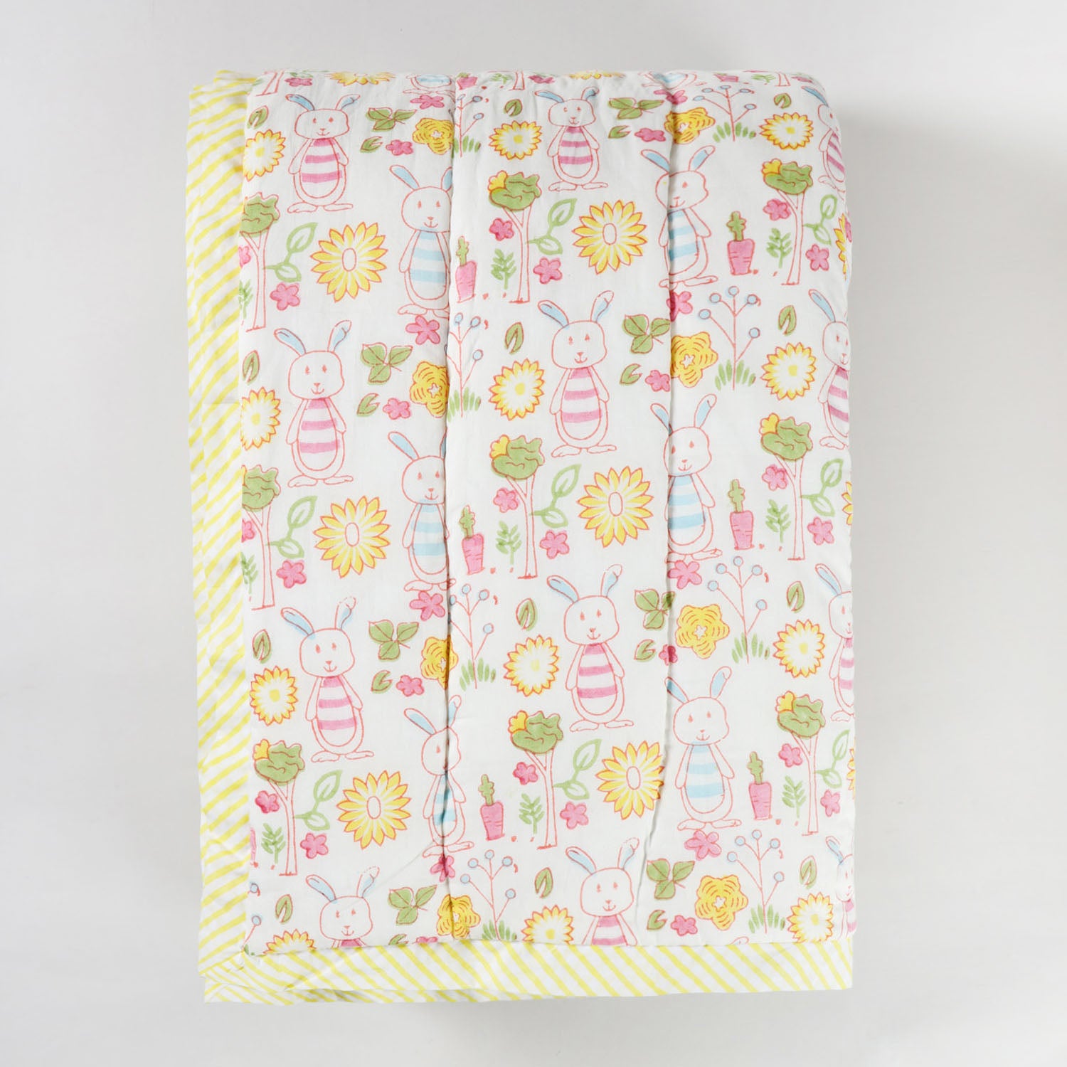 Folded hand block printed cotton quilt featuring bunny garden motifs, highlighting soft texture and lightweight breathable fabric