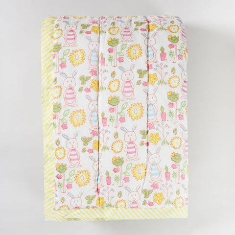 Folded hand block printed cotton quilt featuring bunny garden motifs, highlighting soft texture and lightweight breathable fabric