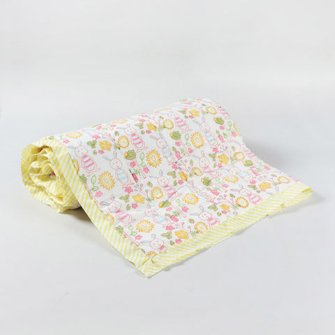 Rolled reversible cotton quilt with bunny garden block print design, showing layered fabric and artisan cotton craftsmanship