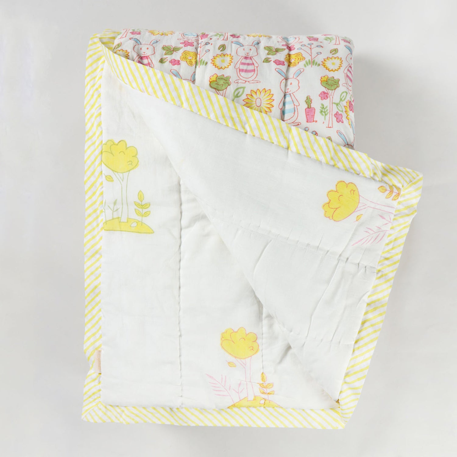 Reversible cotton quilt displaying both front and back designs with bunny garden themed hand block printed motifs