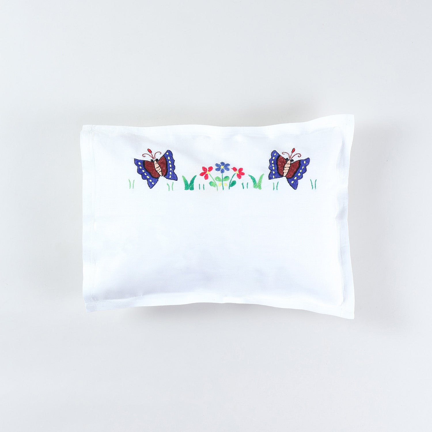 Kids pillow cover with colourful butterfly and floral hand embroidery on a white cotton base from the handmade kids bedding collection