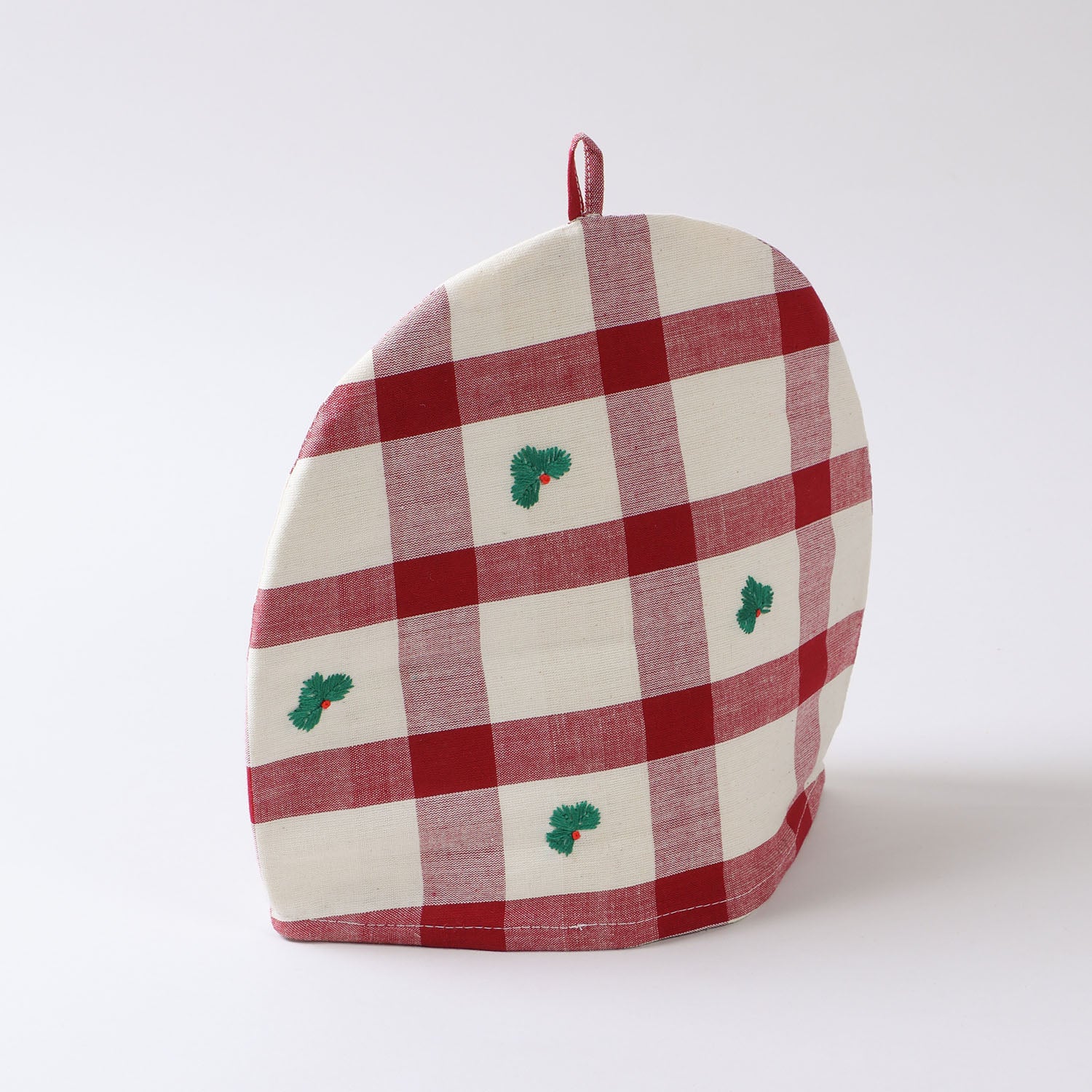 Angled view of a Christmas cotton tea cozy showcasing red and off-white checks and handcrafted stitching details