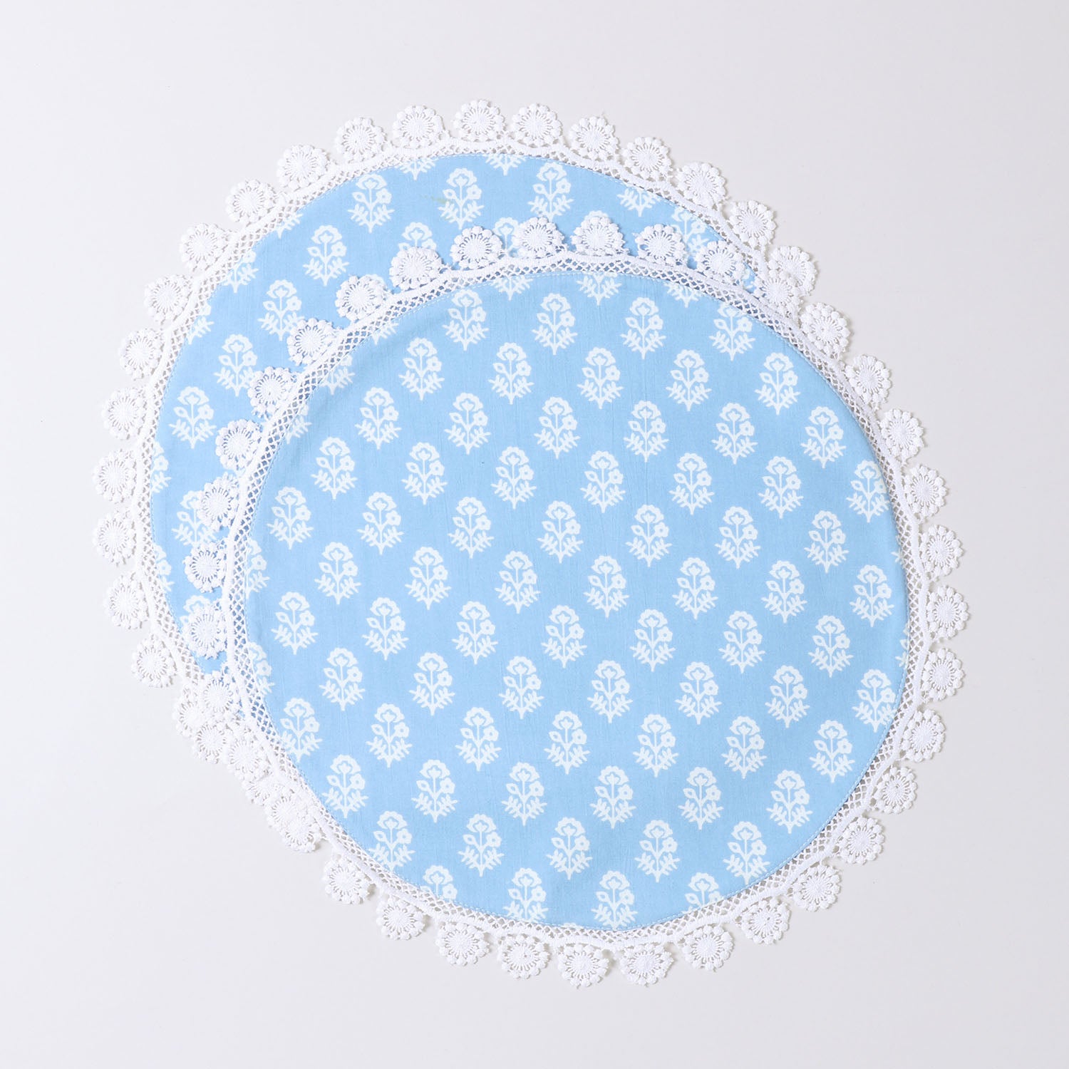 Set of 2 round cotton placemats featuring white block printed Christmas motifs on a blue base with decorative lace edging displayed on a plain background