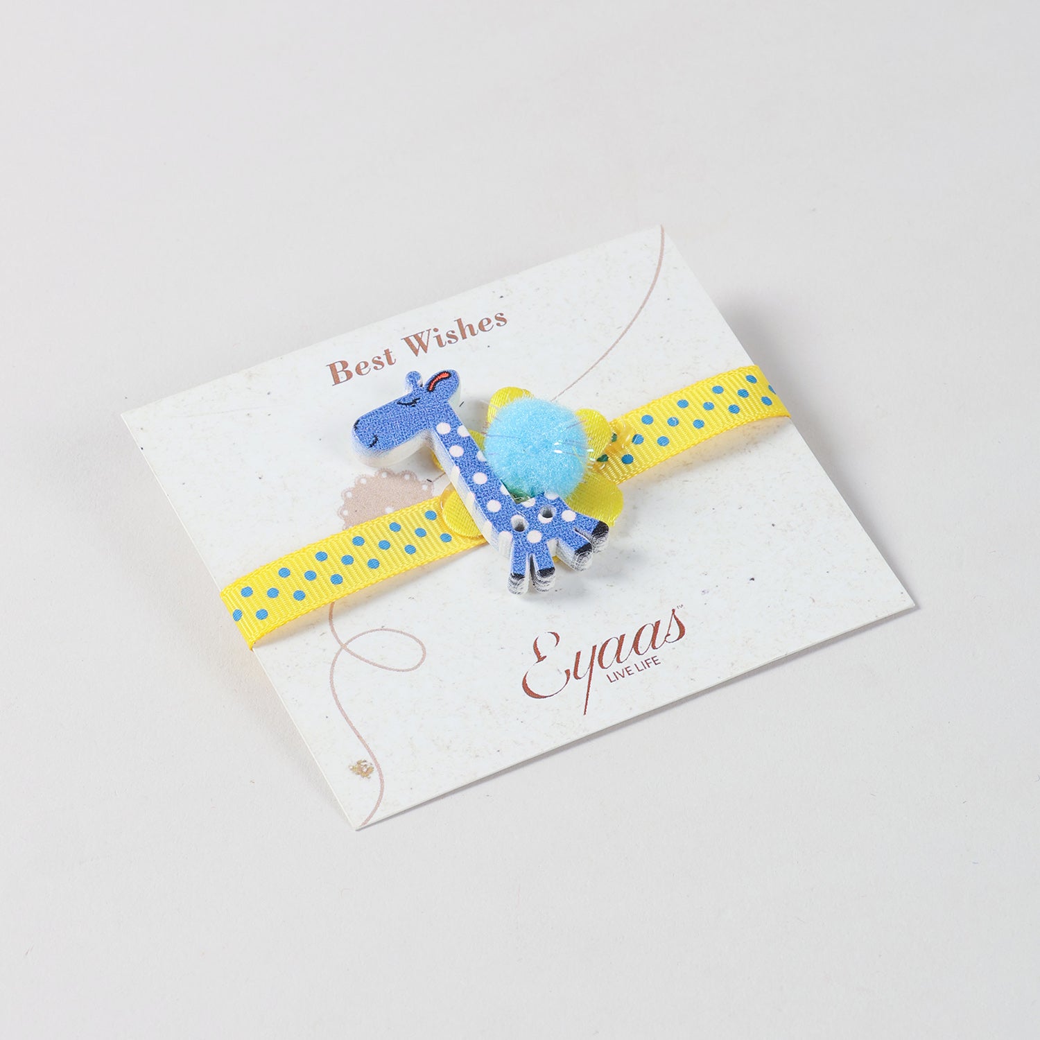 Angled view of the handmade Cobalt Blue Giraffe Wooden Kids Rakhi attached to a festive Best Wishes card for Raksha Bandhan gifting