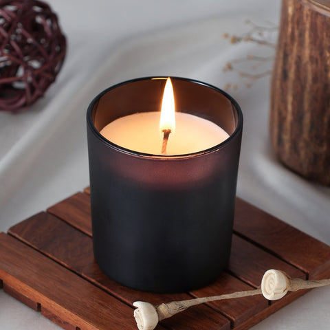 Coffee scented soy wax candle glowing warmly in a glass jar creating a cosy ambience
