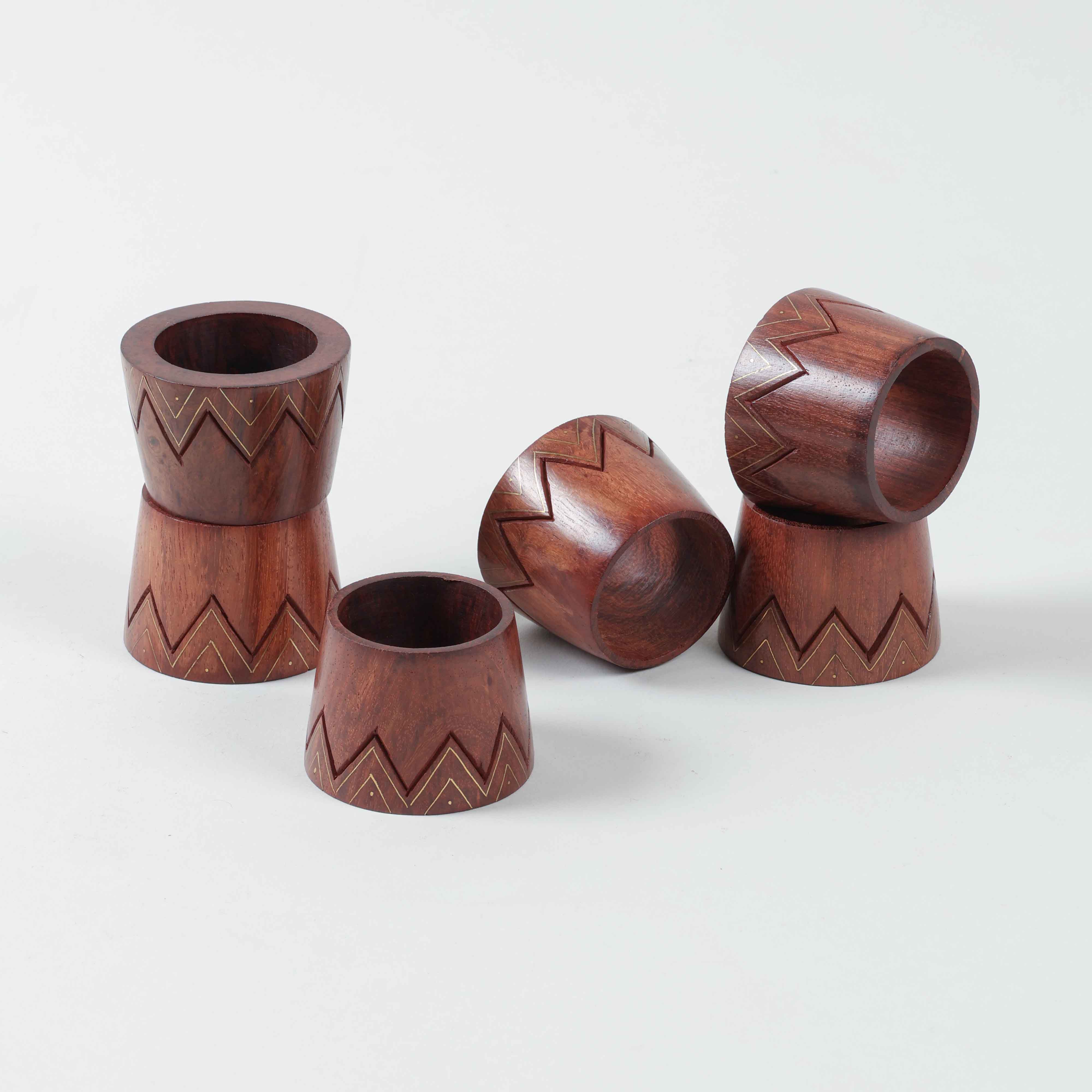Side view of  stacked six conical wooden napkin rings, highlighting tapered shape and brass inlay accents