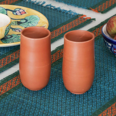 Handmade terracotta glass set of 2 styled on a dining table, featuring naturally cooling clay tumblers for everyday drinks