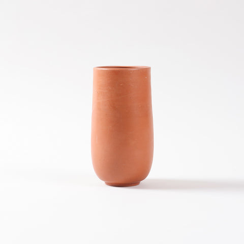 Side profile of a handmade terracotta glass highlighting the curved base, smooth clay finish, and traditional craftsmanship