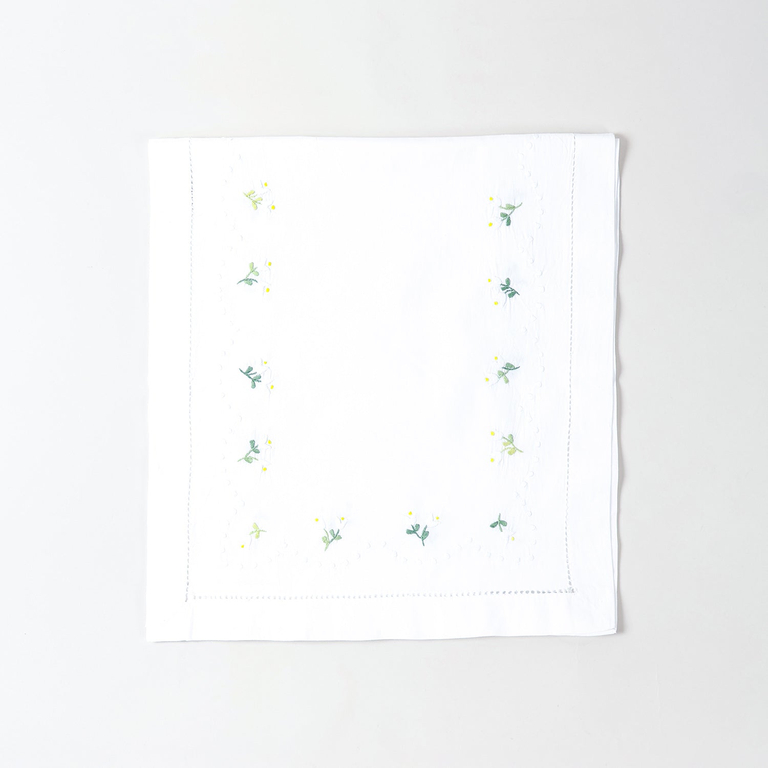 Folded white cotton table runner showcasing delicate daisy embroidery and handcrafted Bengal chikankari detailing