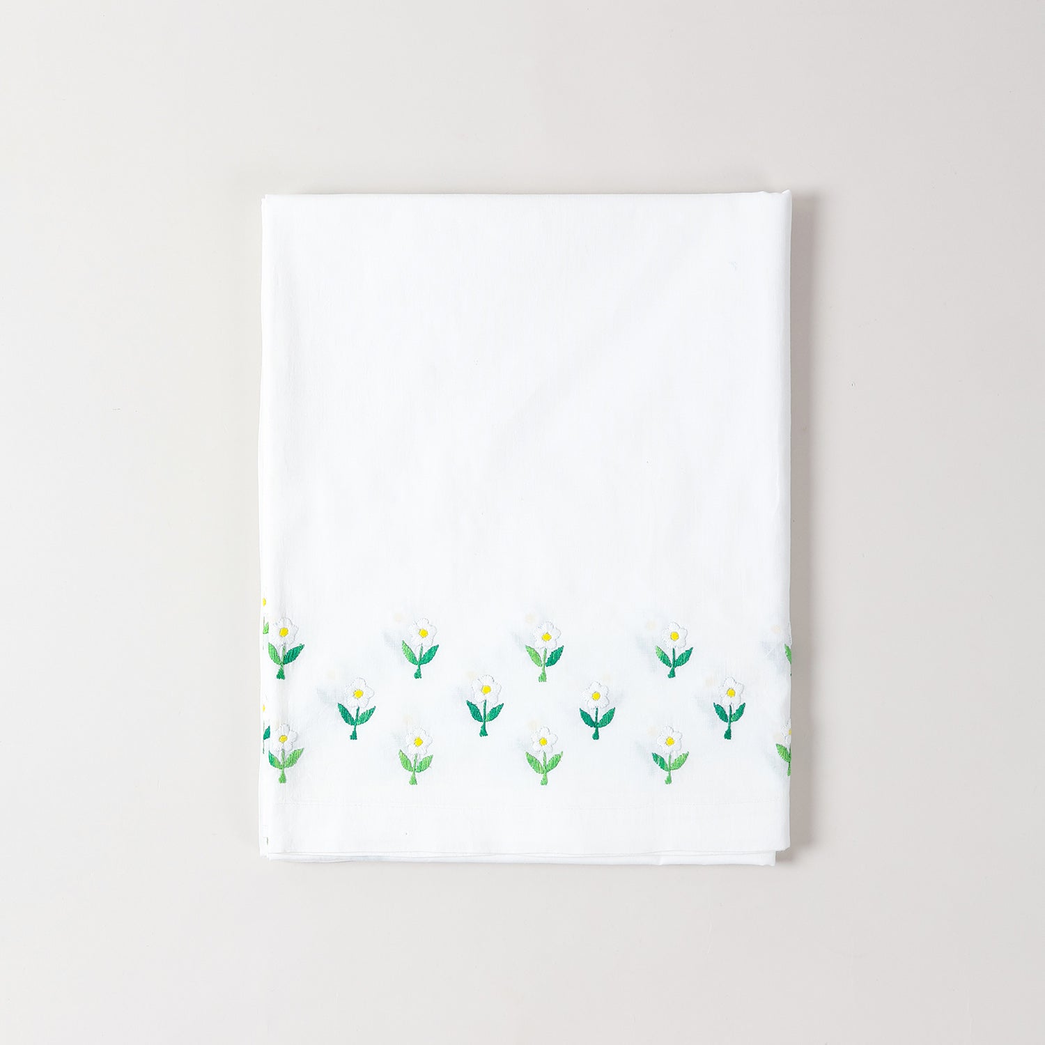Folded embroidered cotton table cloth showcasing daisy floral motifs and handcrafted cutwork craftsmanship