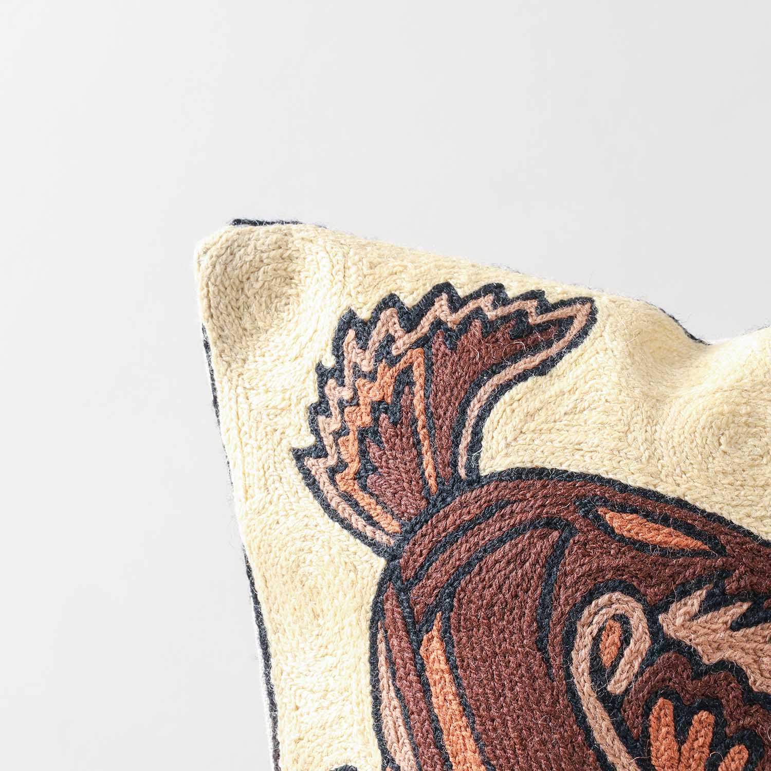 Close-up of deer crewel embroidery, highlighting intricate wool stitching and handcrafted detailing on a beige base