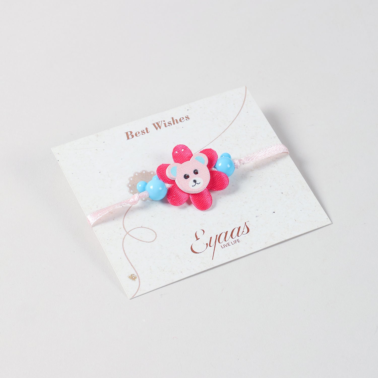 Angled view of the Eco-friednly Wooden Teddy Bear Kids Rakhi Set of 2 in Blue Pink attached to a festive Best Wishes card for Raksha Bandhan gifting