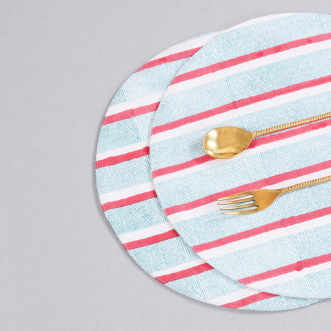 Styled view of a round cotton placemat showcasing red and green stripe block-printed detailing and handcrafted craftsmanship