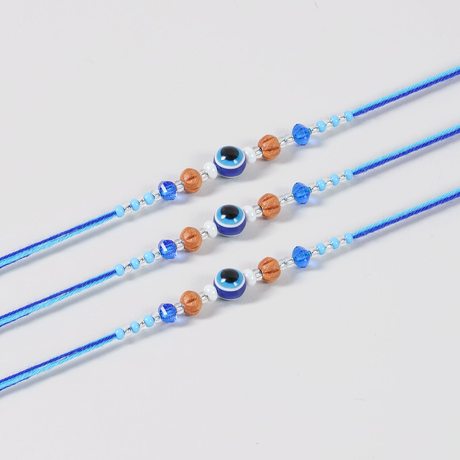 Close-up of the Handmade Evil Eye Rakhi featuring a protective evil eye bead, glass beads, and blue cotton thread.