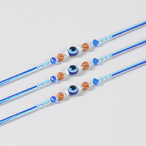 Close-up of the Handmade Evil Eye Rakhi featuring a protective evil eye bead, glass beads, and blue cotton thread.