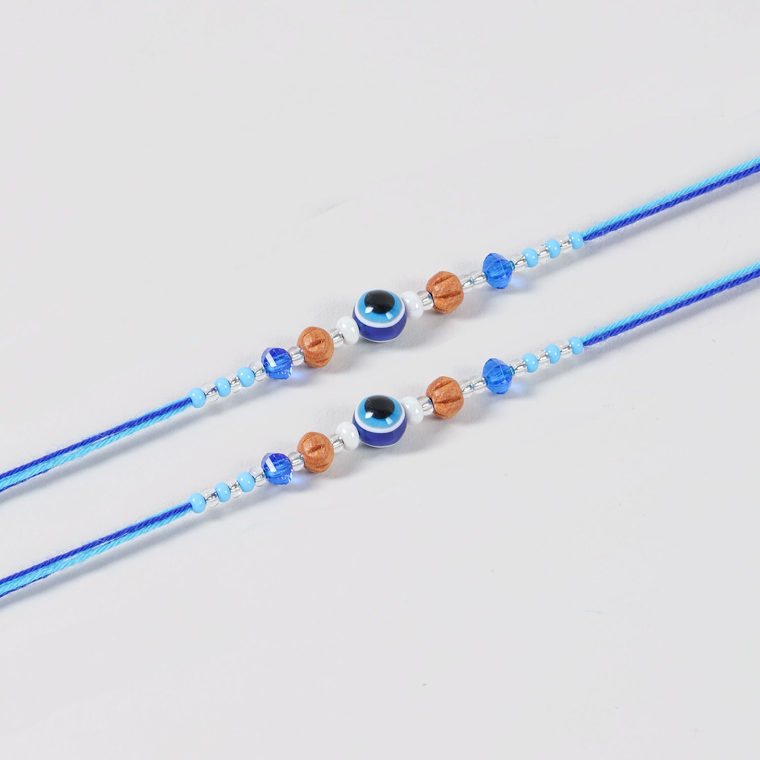 Close-up of the Handmade Evil Eye Rakhi featuring a protective evil eye bead,, decorative beads, and blue cotton thread.