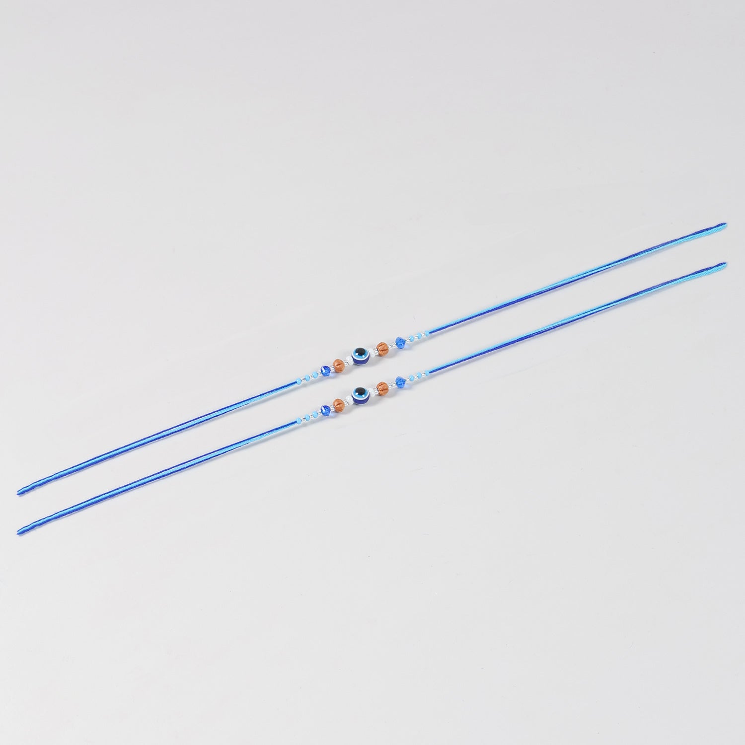Full-length view of the Handmade Evil Eye Rakhi with Decorative Beads Set of 2, showcasing handcrafted beadwork and blue cotton thread.
