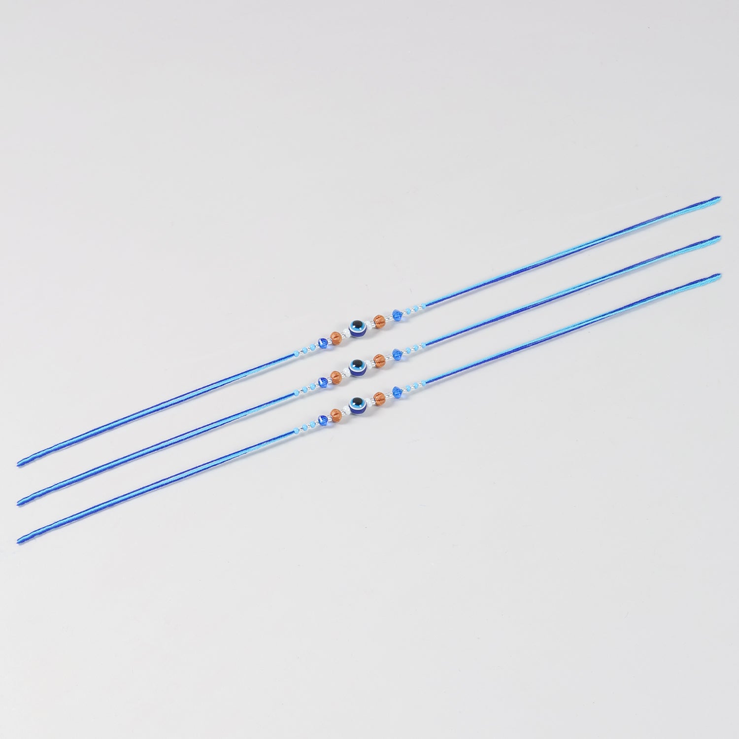 Full-length view of the Handmade Evil Eye Rakhi with Beads Set of 3, showcasing handcrafted beadwork and blue cotton thread.