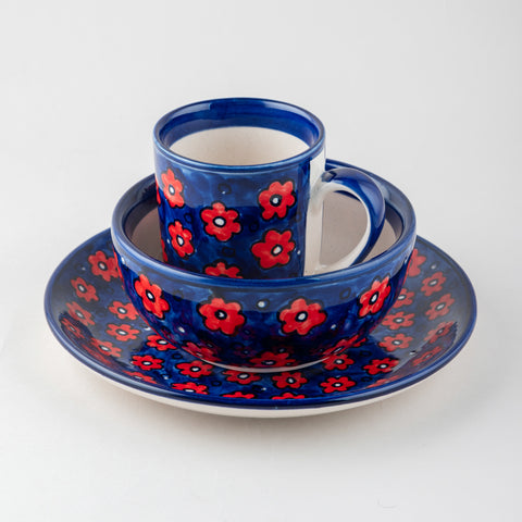 Stacked position of a floral ceramic breakfast set showcasing a matching mug, bowl, and plate with coordinated handpainted designs