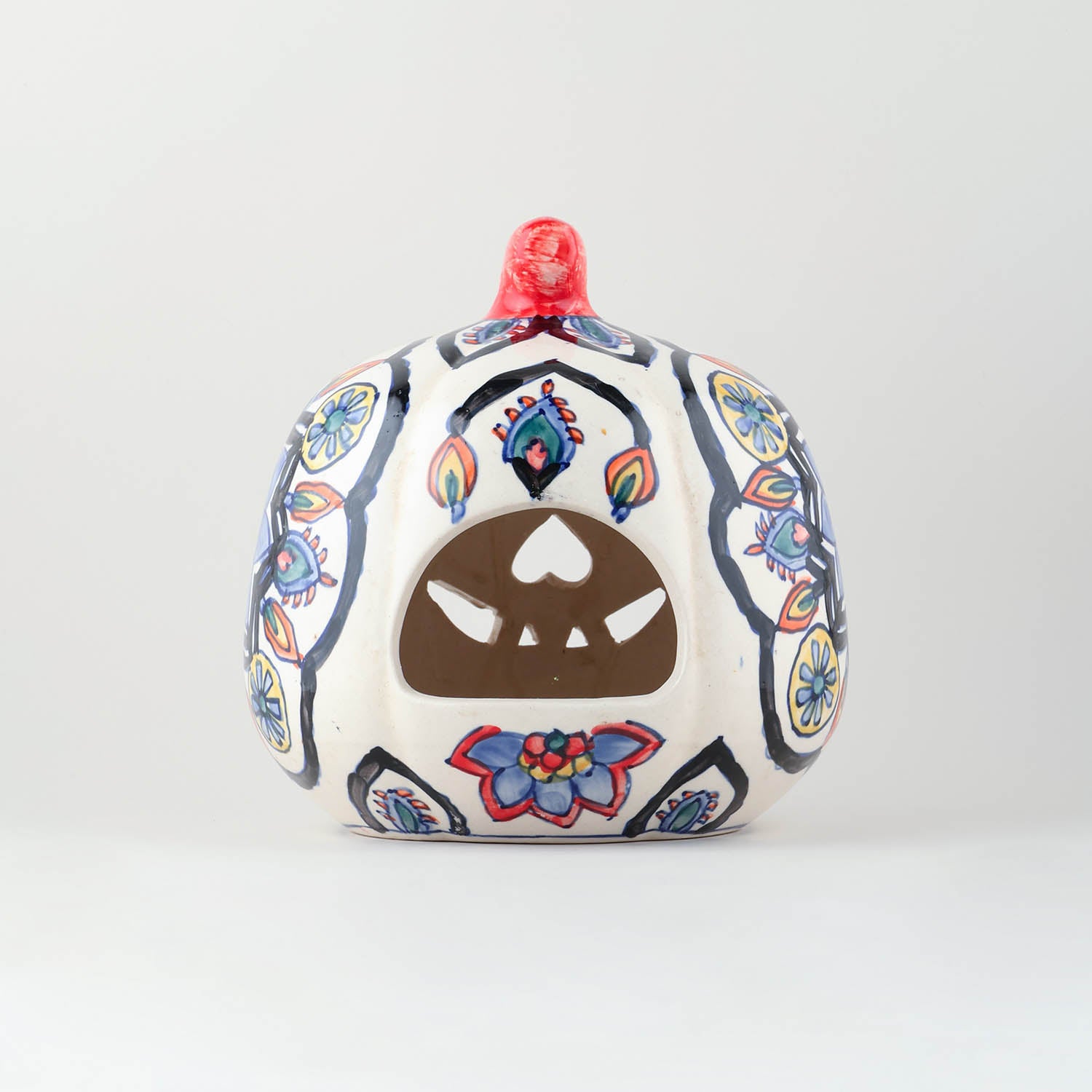 Multi-coloured ceramic pumpkin tea light holder with a back opening and hand-painted floral patterns viewed from the backside.