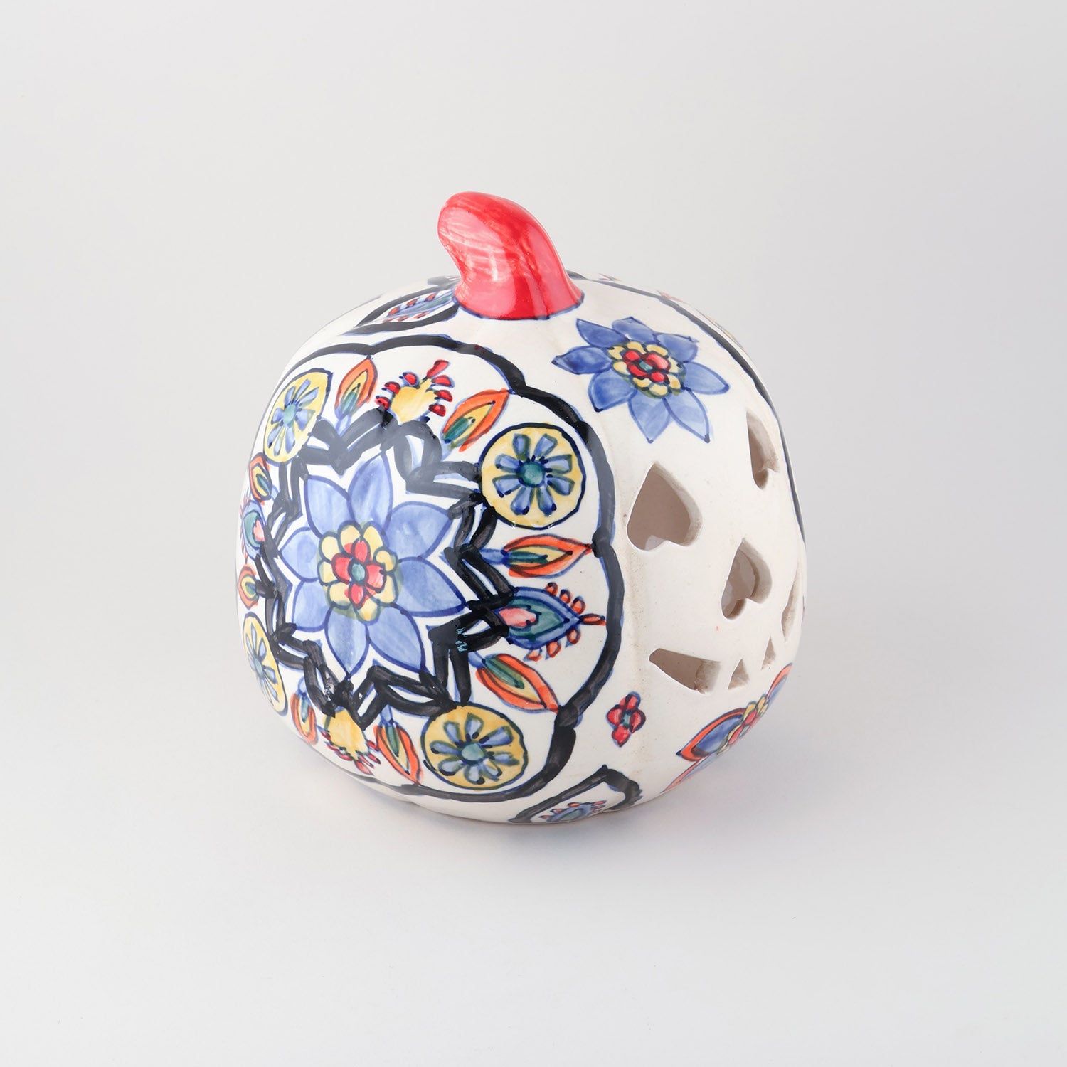 Side view of a hand-painted ceramic pumpkin t-light holder featuring floral motifs and decorative cutwork