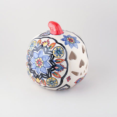 Side view of a hand-painted ceramic pumpkin t-light holder featuring floral motifs and decorative cutwork